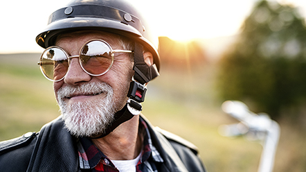 Homem idoso com capacete e oculos escuro.