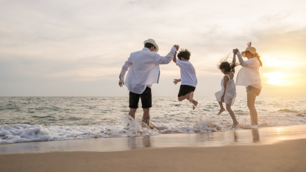 Família pulando onda na praia.